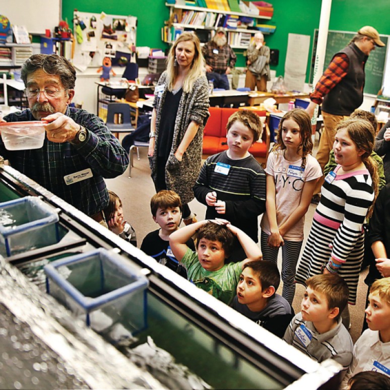 HOLLY PELCZYNSKI - BENNINGTON BANNER Third graders at the Village School of North Bennington watch in anticipation as Trout eggs get placed in the fish tank in their classroom. The students are learning about the lifecycle of Trout from fishing expert Barry Mayer, volunteer and educated with the Southern Vermont chapter of Trout unlimited, after the eggs are placed they will stay in the classroom, grow, and then be released back into the wild.